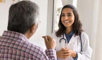 Older patient talking with a young, happy doctor.